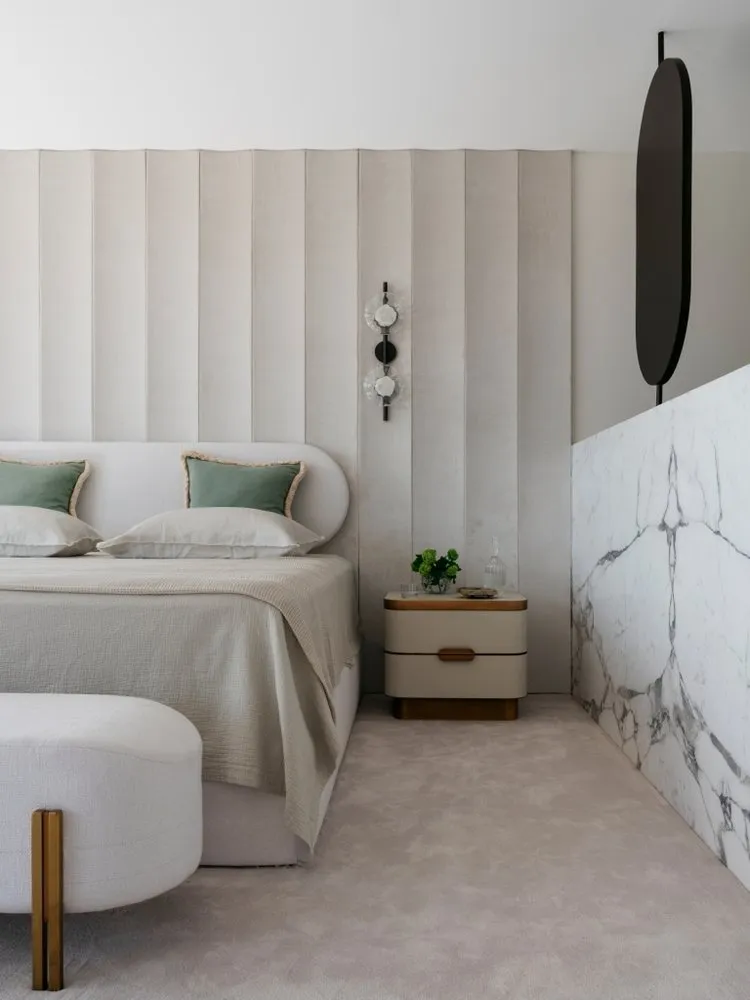 A modern bedroom featuring a neutral-toned color palette, plush bedding, and minimalist decor.