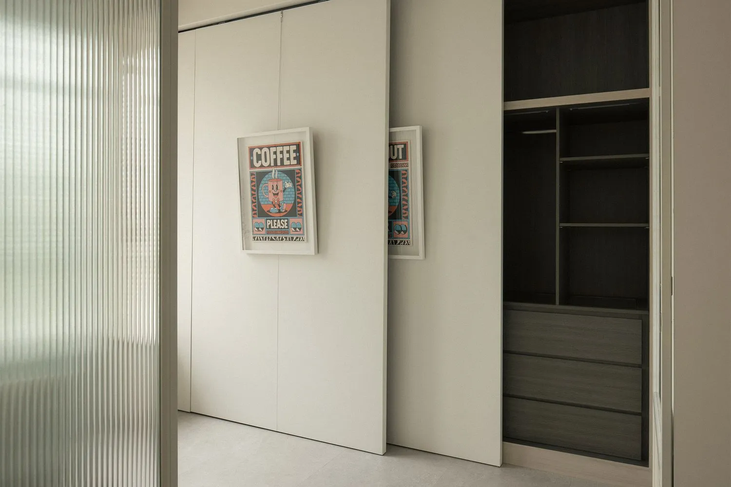 Minimalist modern closet with white sliding doors and black minimalist design, featuring framed posters.