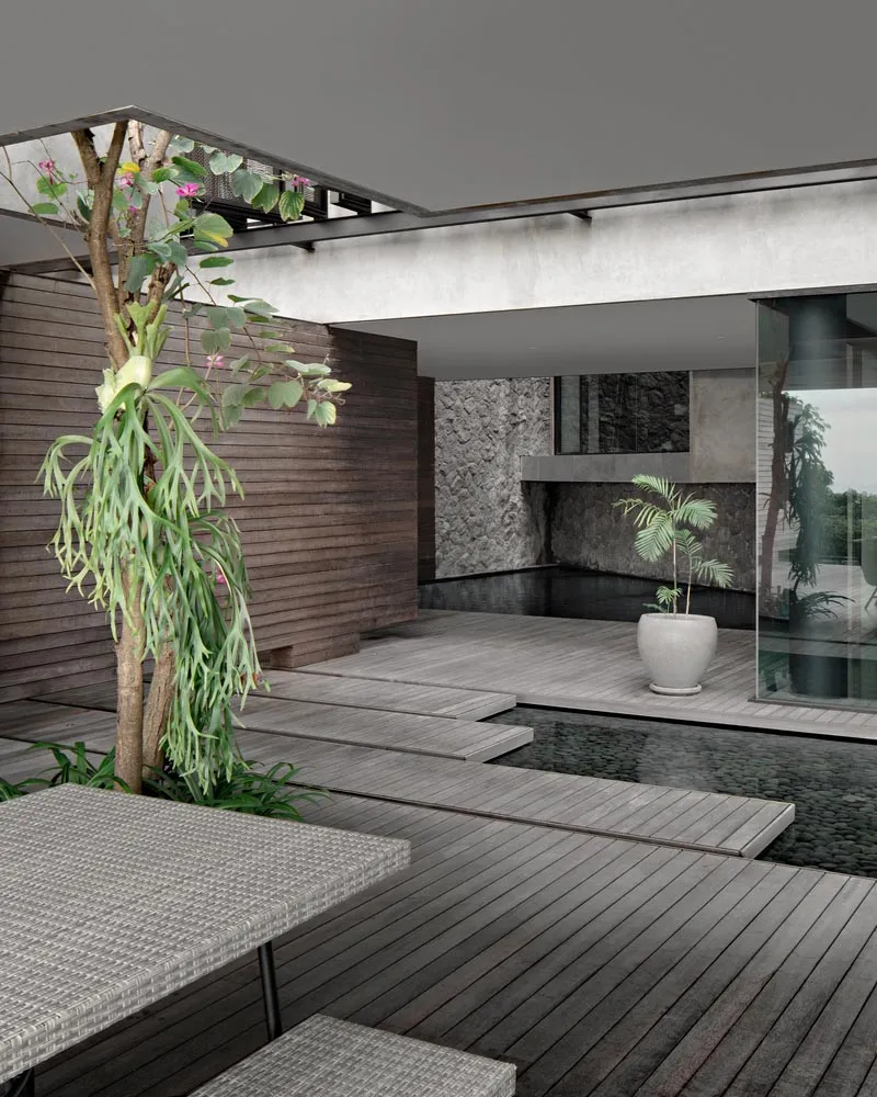 An industrial-style house exterior with a wooden deck, glass walls, and a small swimming pool.