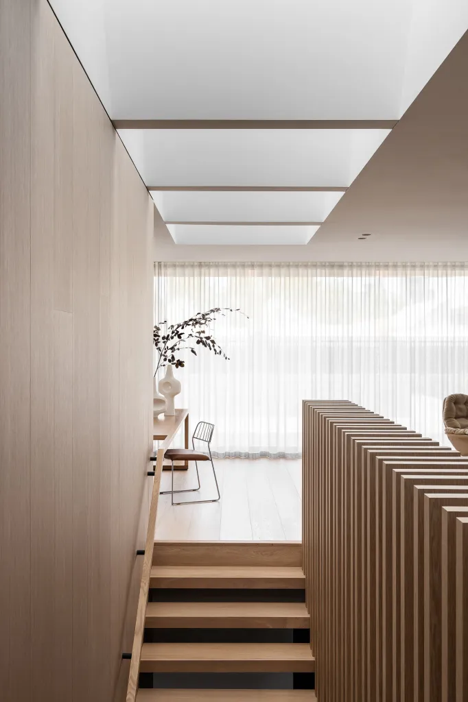 Modern minimalist living space featuring wooden stairs and neutral tones.