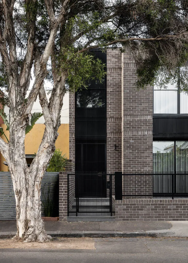 A modern residential facade featuring gray brick walls and black framed windows.