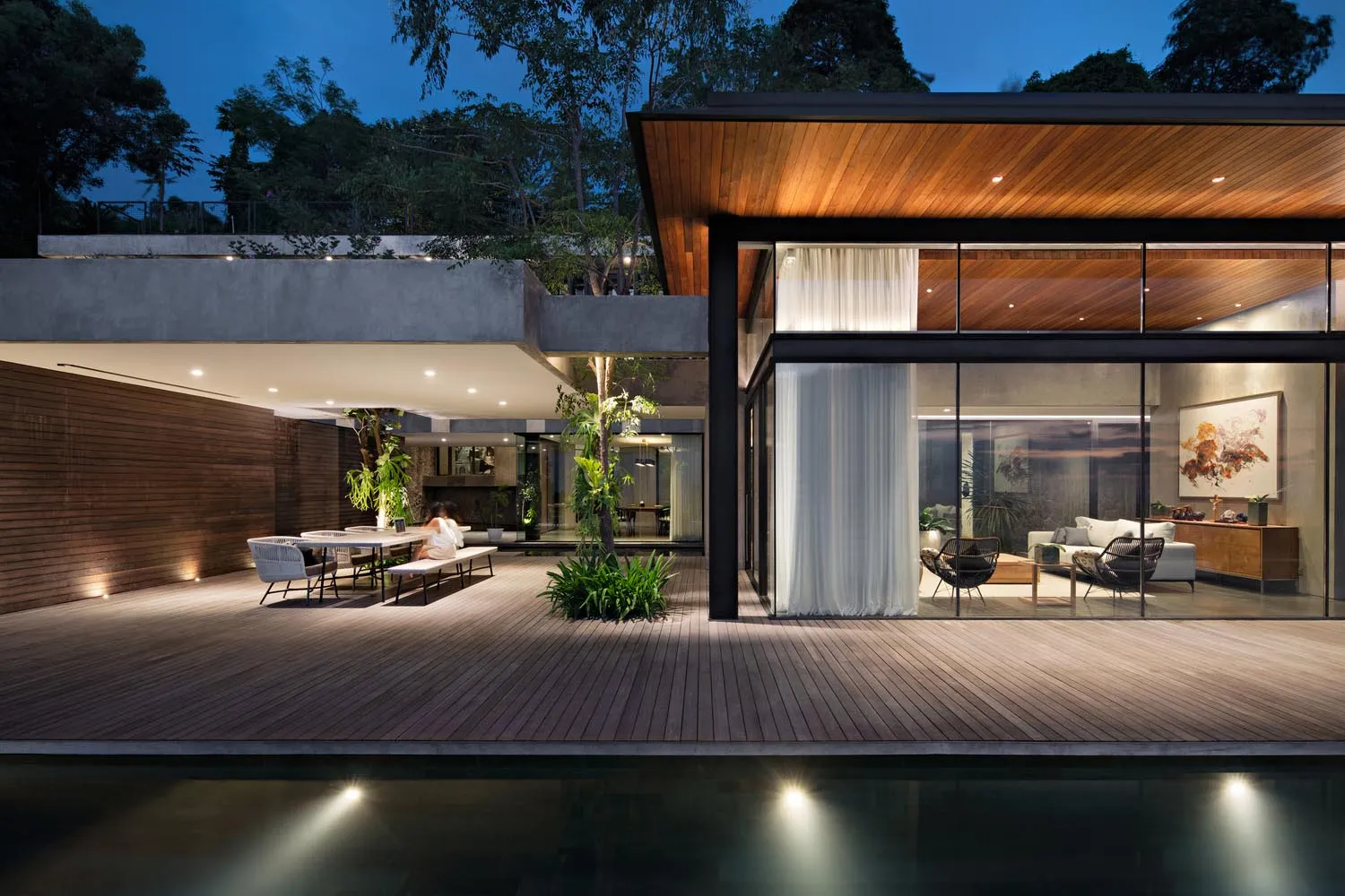 Modern residential space featuring wooden flooring, glass walls, and concrete elements.