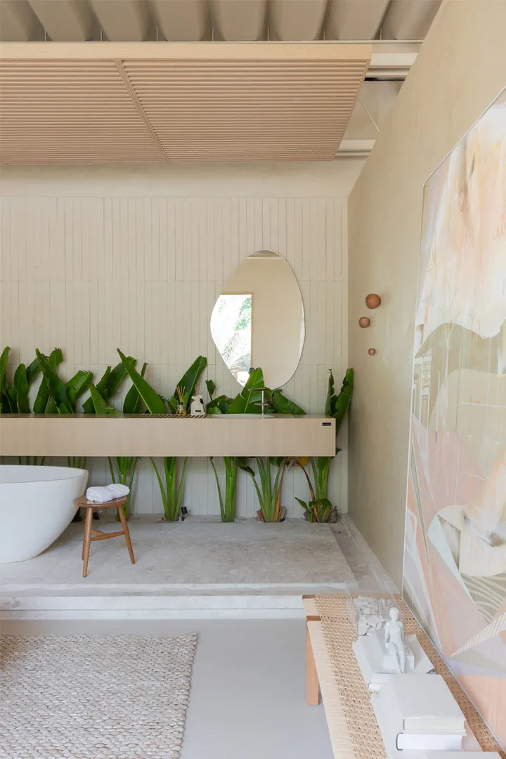 A minimalist bathroom with a wooden vanity, concrete floor, and lush green plants