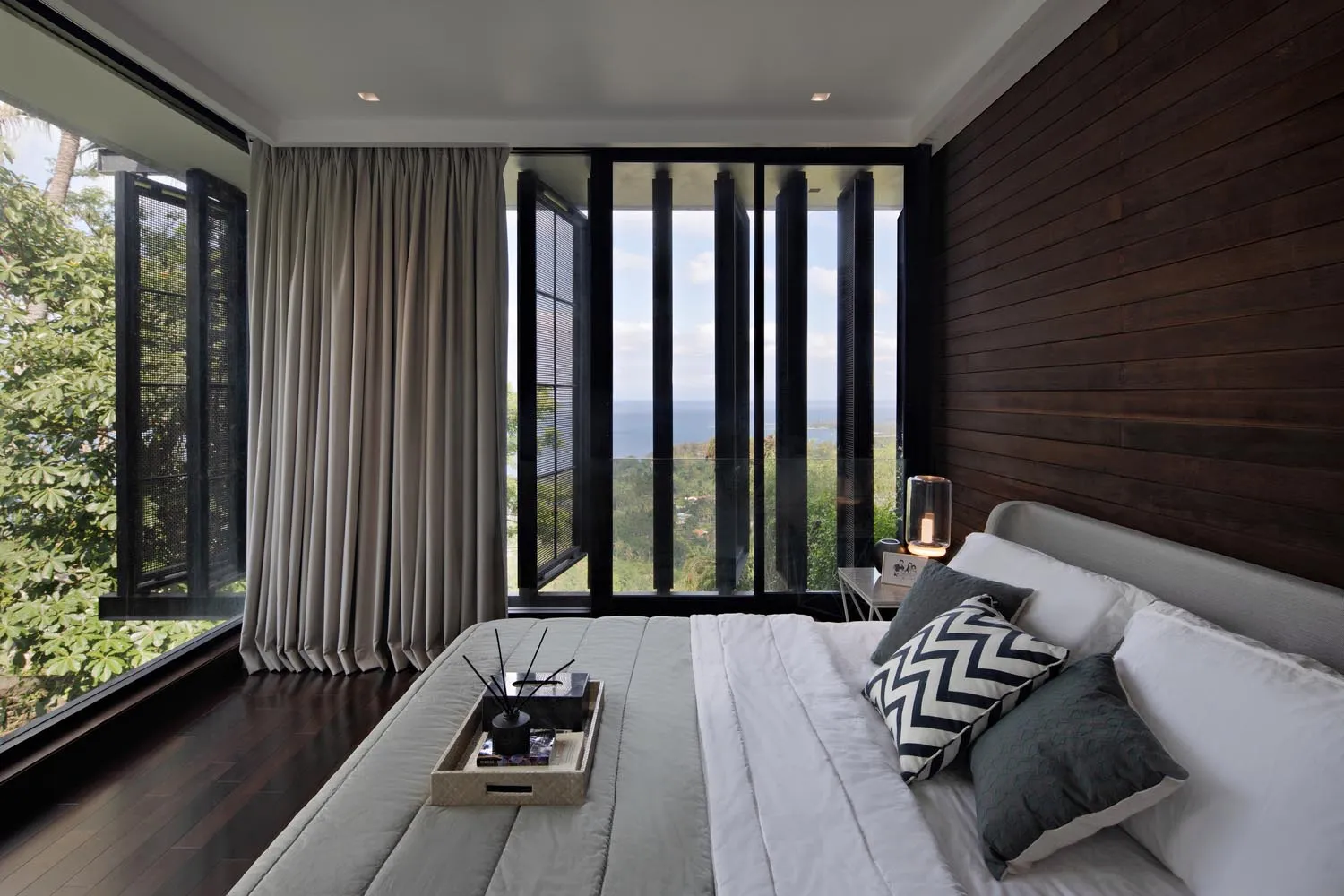 A minimalist bedroom featuring taupe and gray tones, with a bed, pillows, and a tray on the bed.