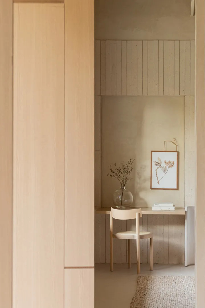 A minimalist office with a wooden wall, chair, and small desk.