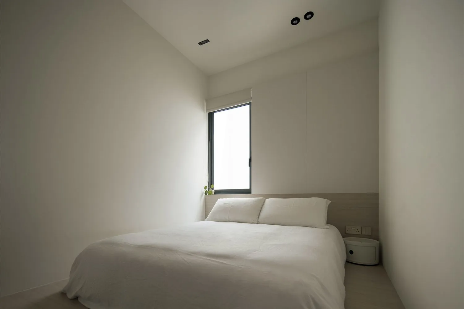 A minimalist bedroom featuring a large bed with white bedding and a neutral color palette.