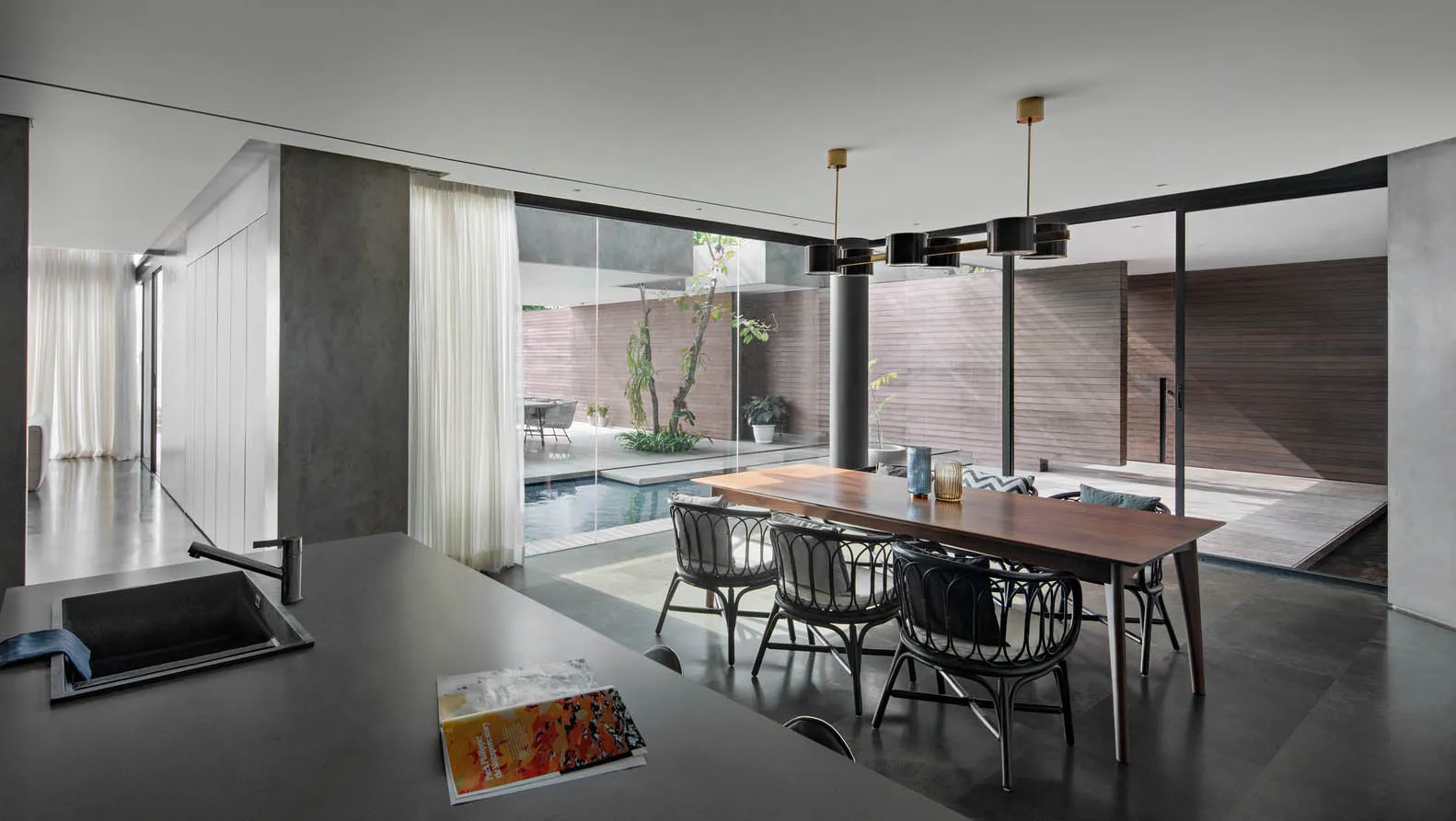 Modern minimalist residential interior featuring glass walls, concrete and steel furniture and fixtures.
