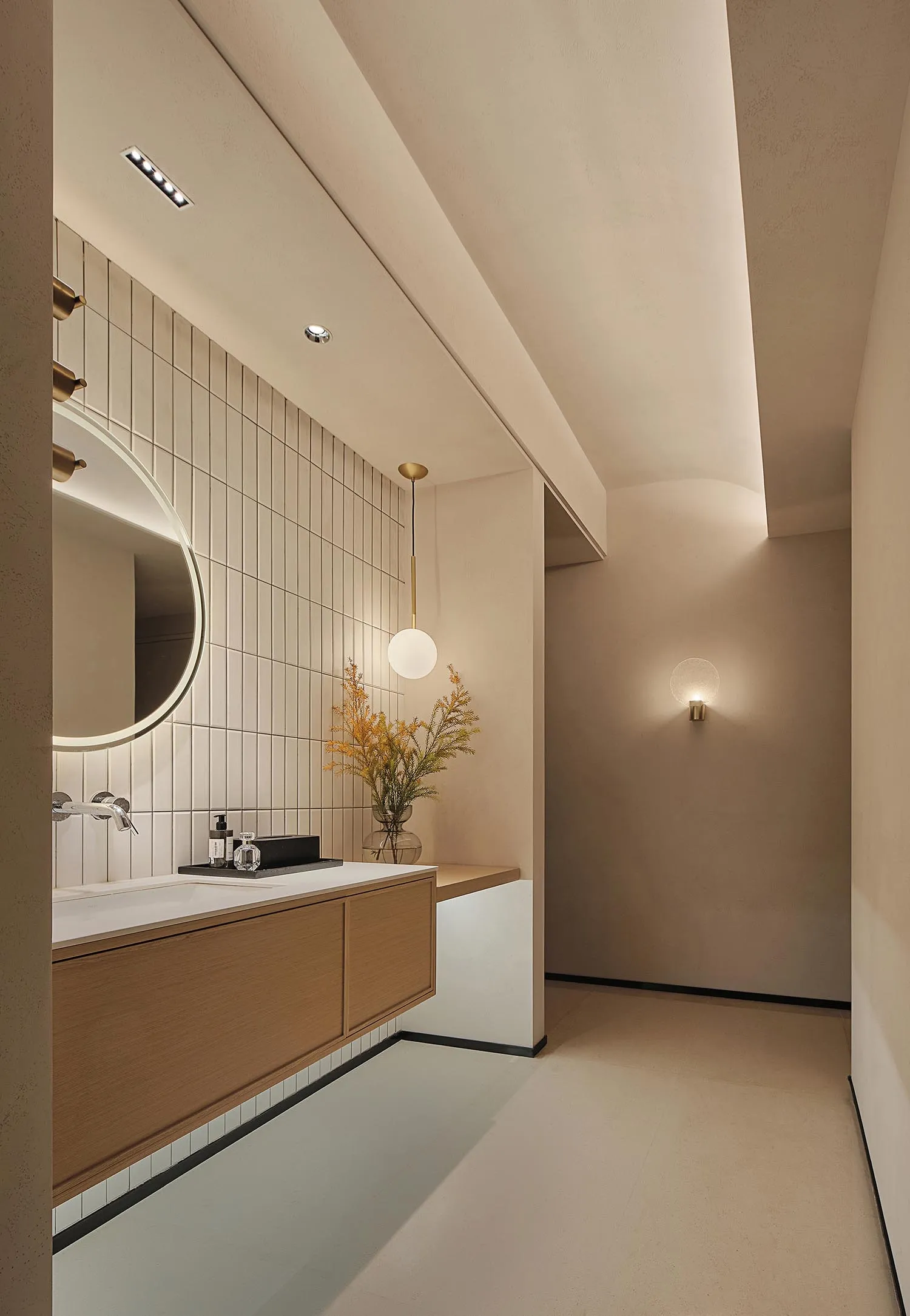 Modern minimalist bathroom featuring ceramic tiles, floating vanity, and spherical pendant light.