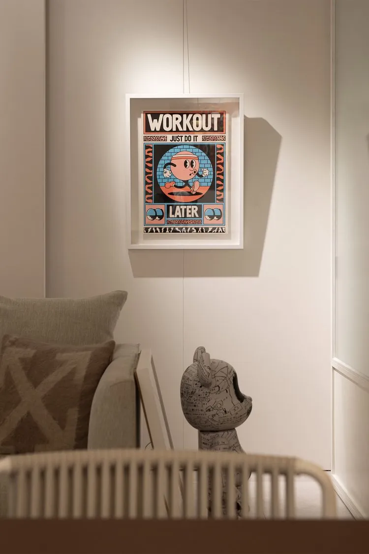 A minimalist poster with a cartoon character and the text 'Workout Later', framed and hung on a wall.