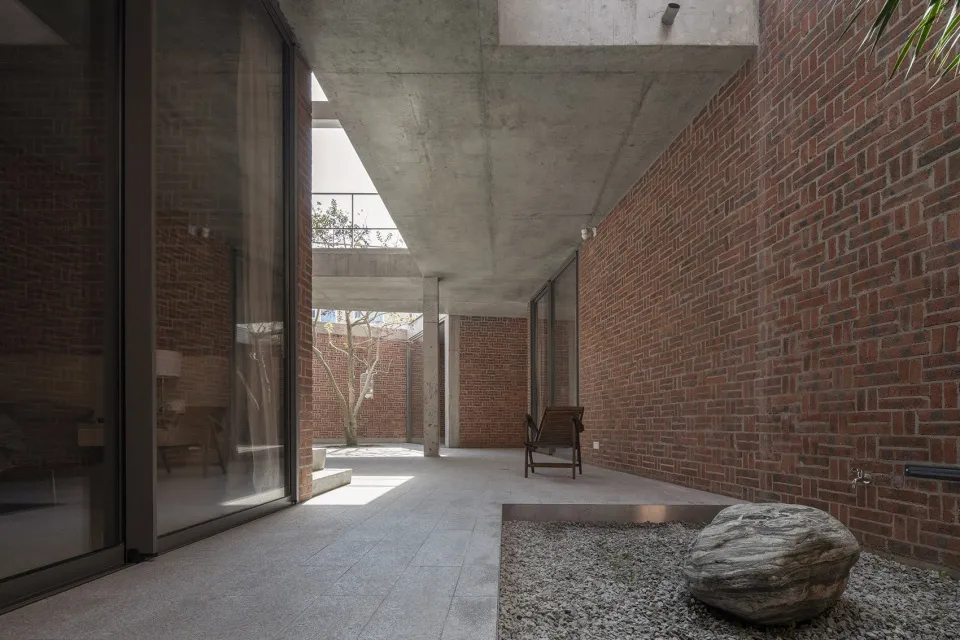 Modern industrial-style loft with exposed concrete ceiling, brick walls, and a concrete floor, featuring minimalist furniture