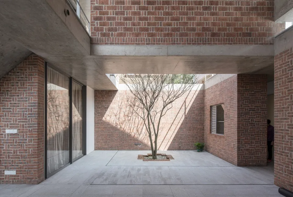 Modern interior space featuring brick walls and a tree in a courtyard.