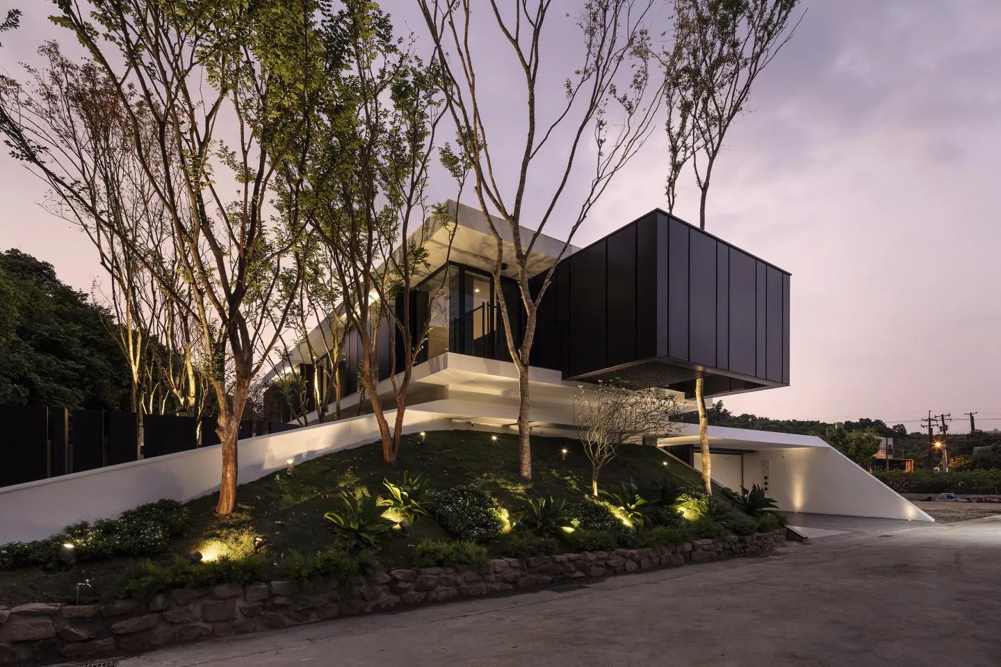 A modern residential building with concrete and glass features at dusk.