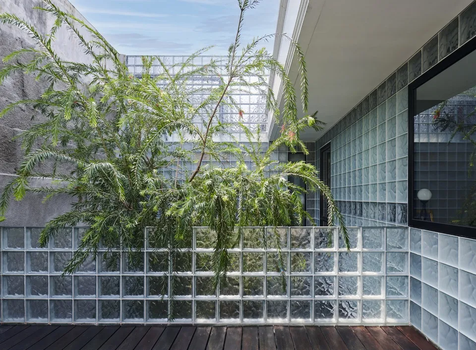 A minimalist interior featuring a glass block wall, wooden deck, and tiled wall.