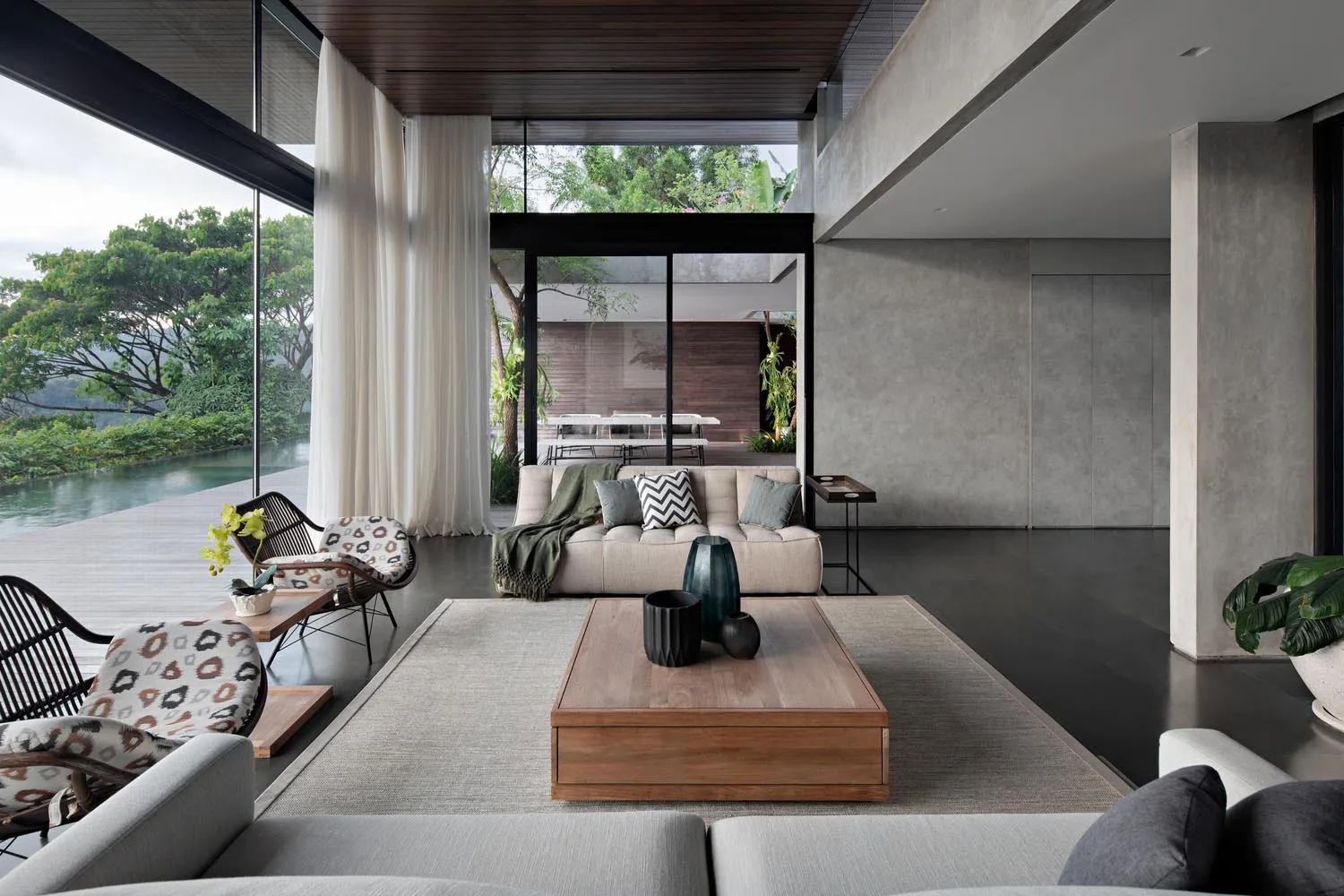 A modern living room with concrete and wood materials, featuring a comfortable sofa, a minimalist coffee table, and large win