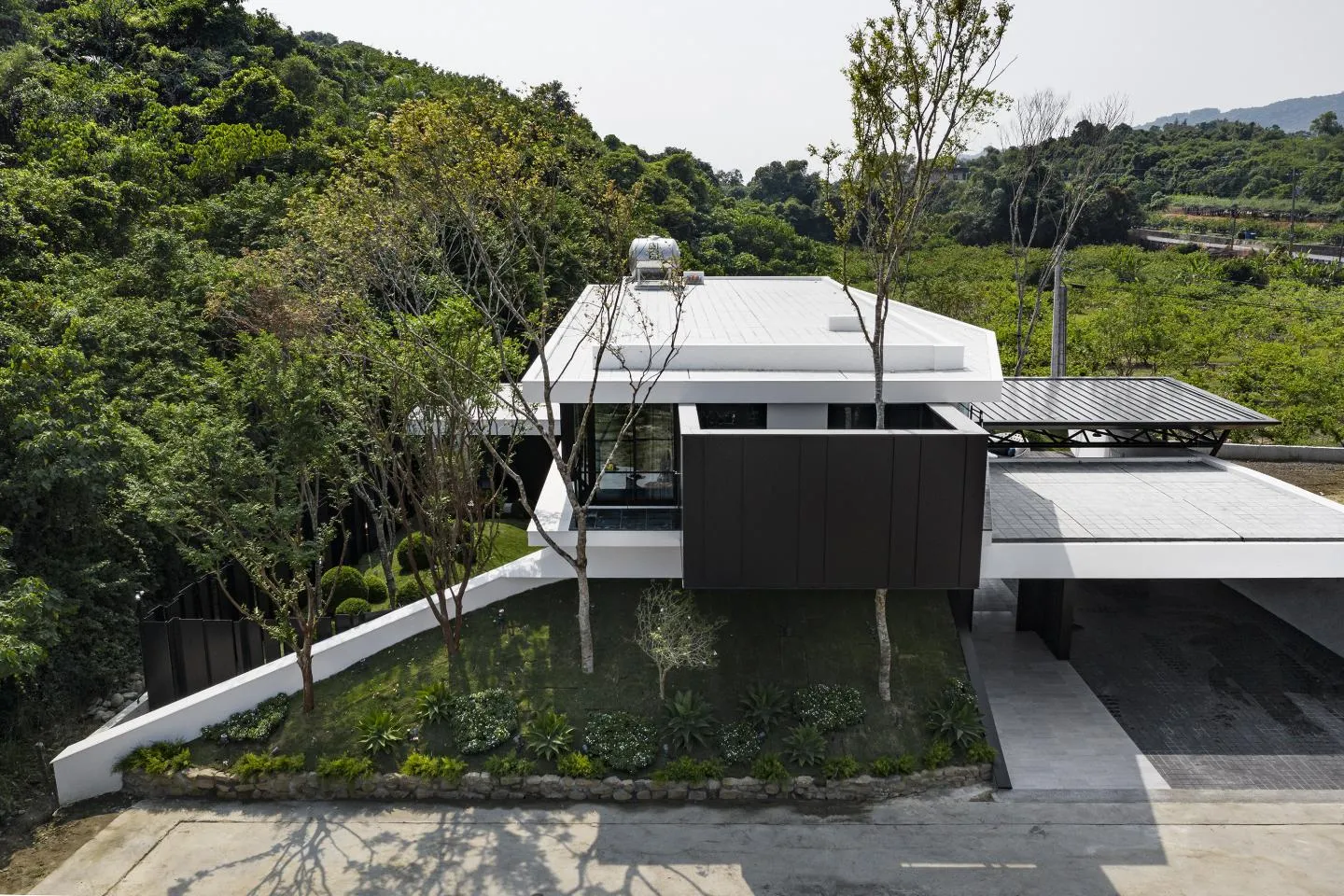 A modern house with a concrete exterior and greenery around it.