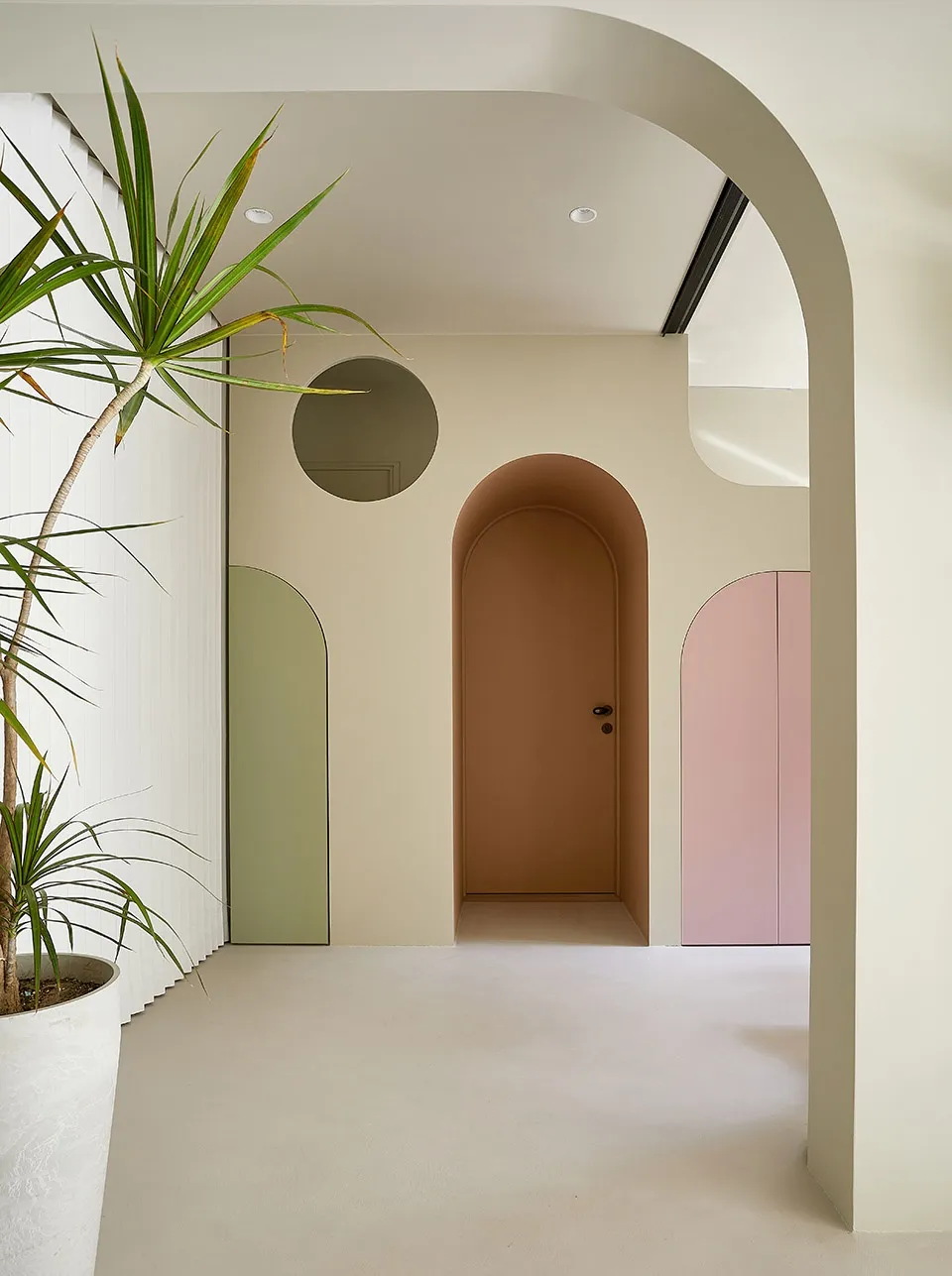 Architectural design featuring minimalist white walls with curved arches and potted plants.
