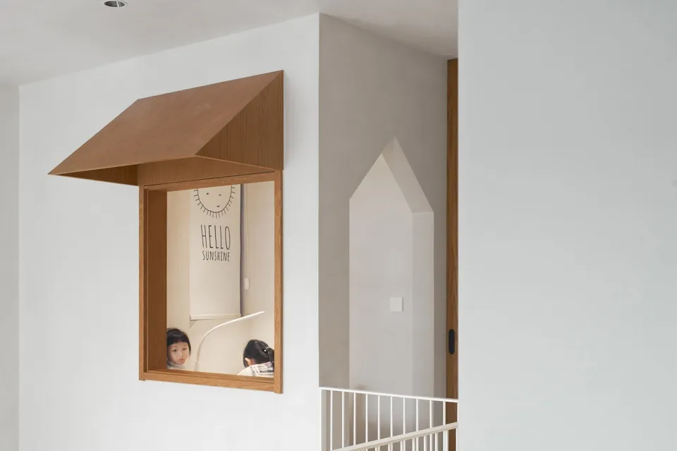 A modern children's playroom featuring a wooden window and two children playing.
