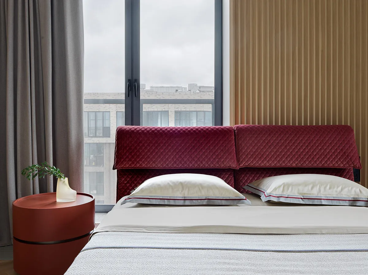 A modern minimalist bedroom featuring a fabric upholstered headboard and white bedding.