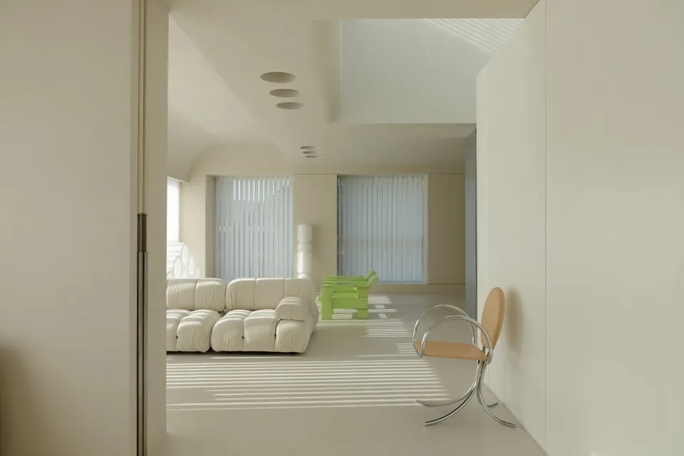 A modern white living room with a white sofa and green chairs.