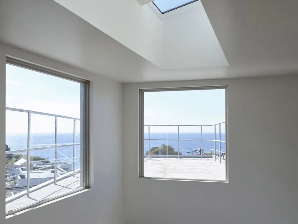 A minimalist interior with large windows showcasing glass materials and ocean views.