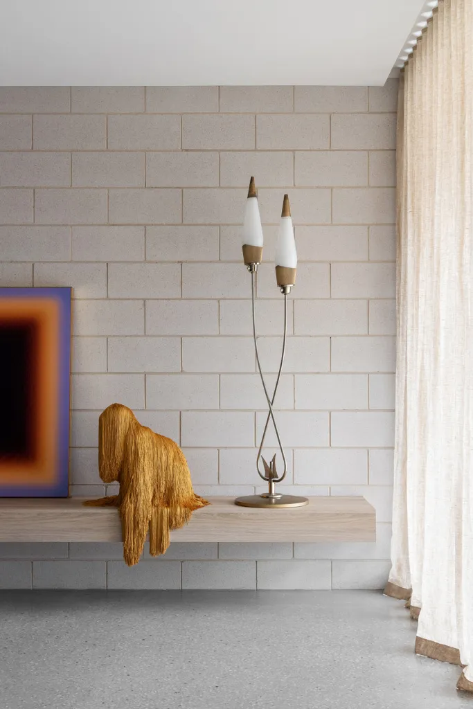 Minimalist living room featuring a concrete counter with a modern lamp and a textured golden throw