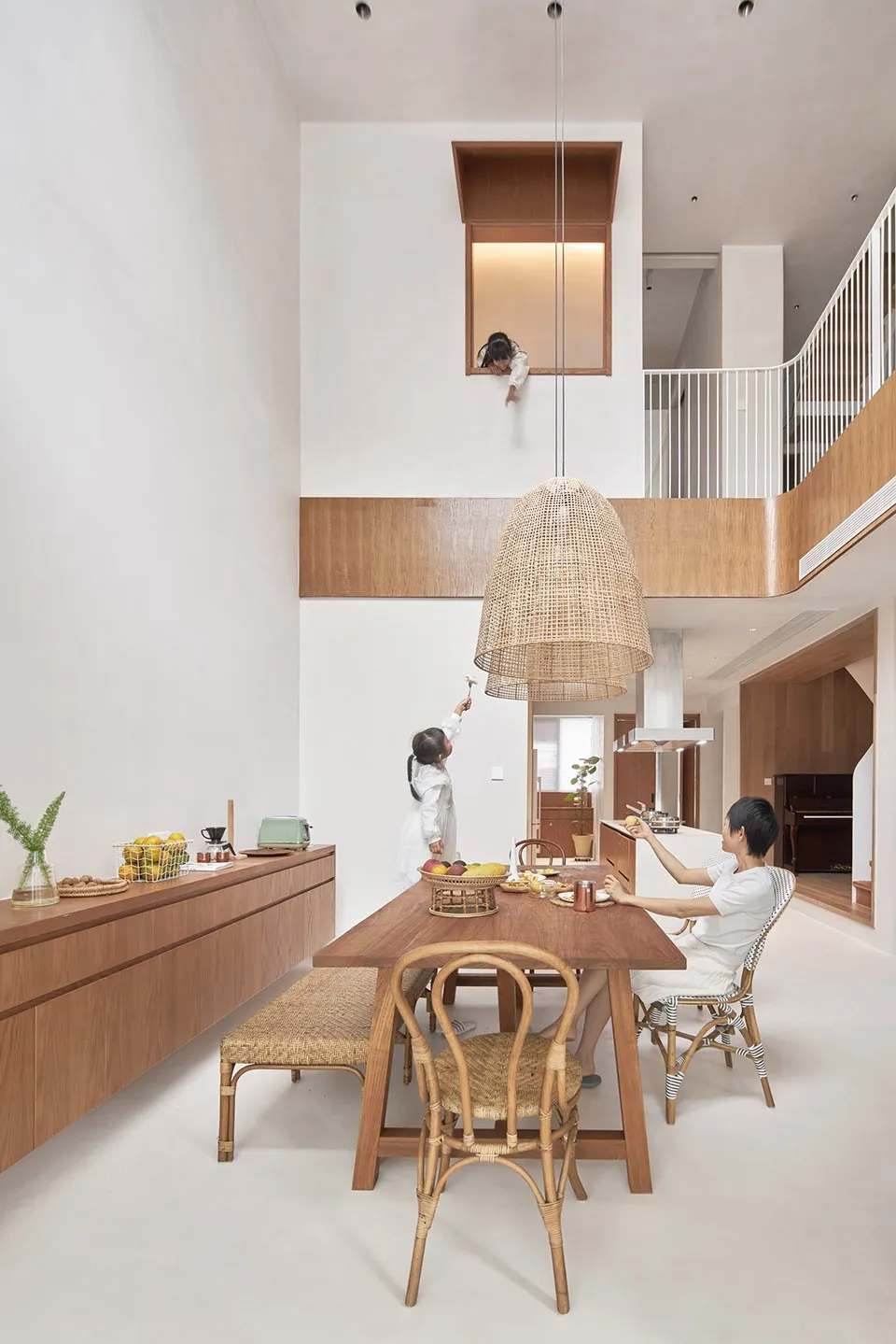 A modern dining room featuring wooden furniture and a hanging rattan pendant light.