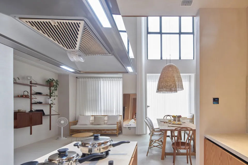 A modern living/dining/kitchen space with a minimalist design, featuring wicker furniture, a wooden dining table, and an acry