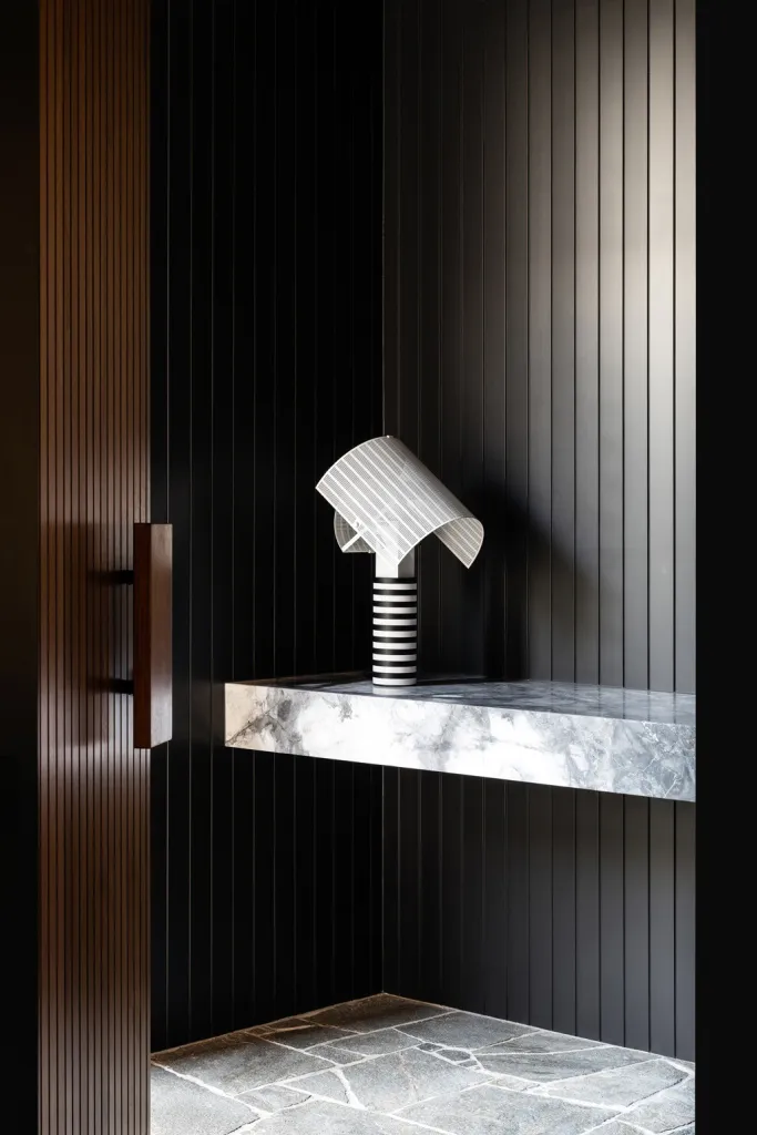 A minimalist entryway featuring a modern lamp and marble countertop