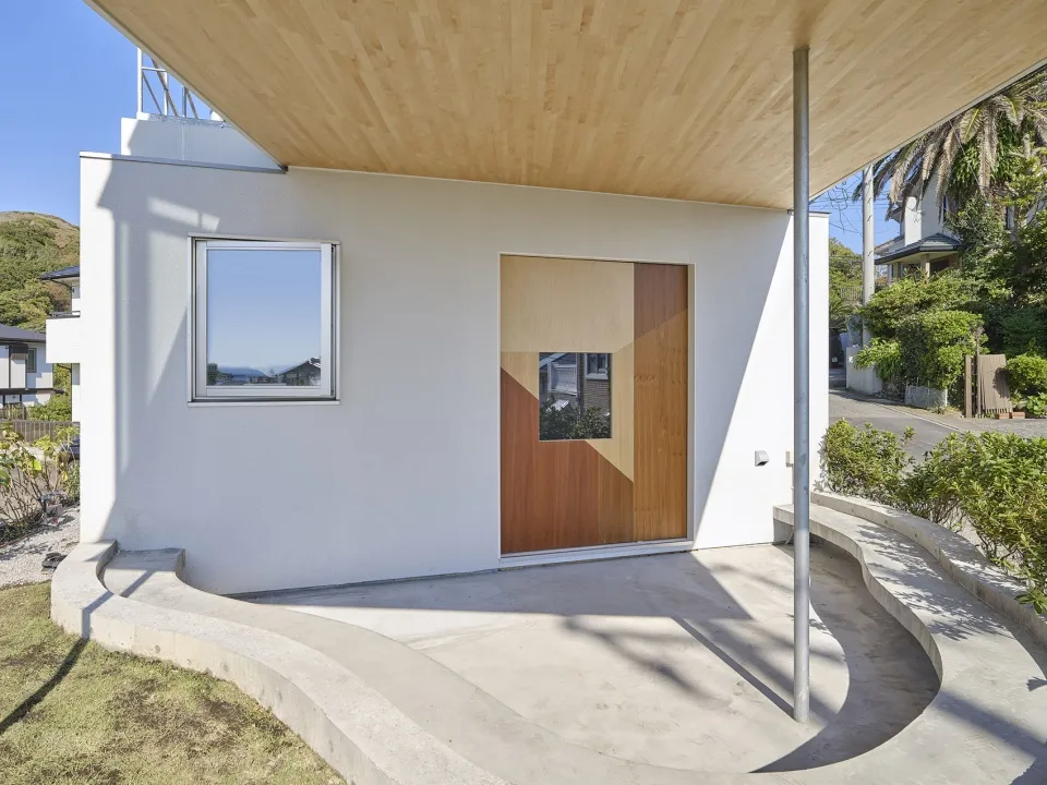 A modern residential building featuring wooden accents, concrete walkways, and large windows.