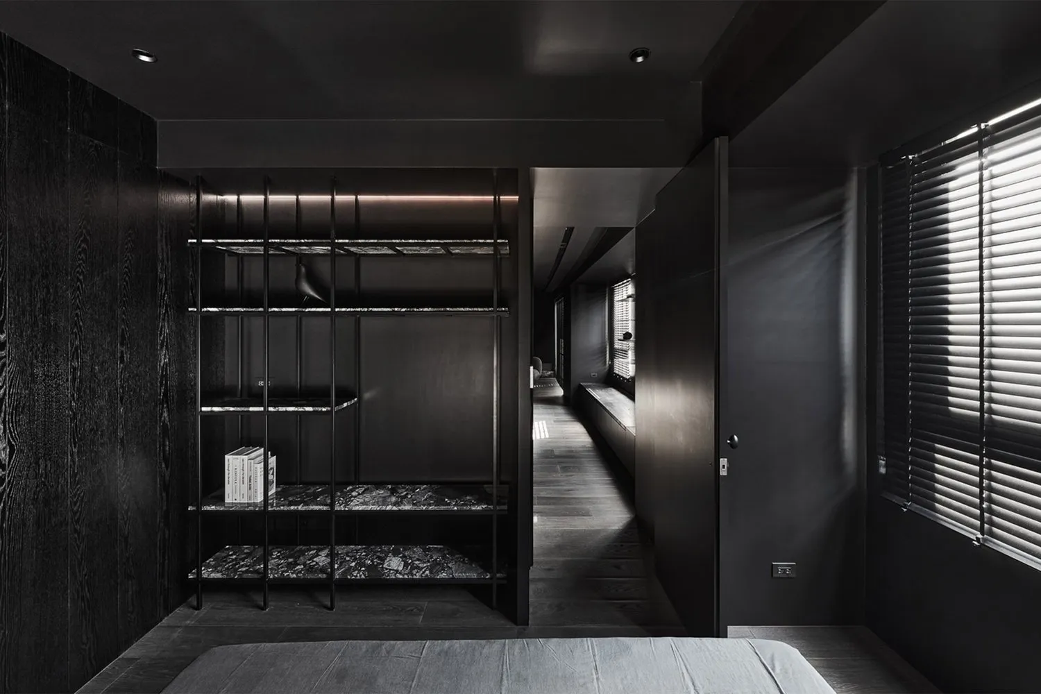 A modern bedroom featuring a black bookshelf made of metal, marble, and wood.
