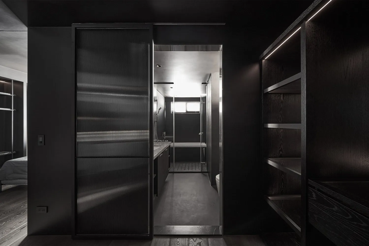 Modern bathroom featuring dark glass walls and floor, with a sleek design and minimalistic aesthetic.