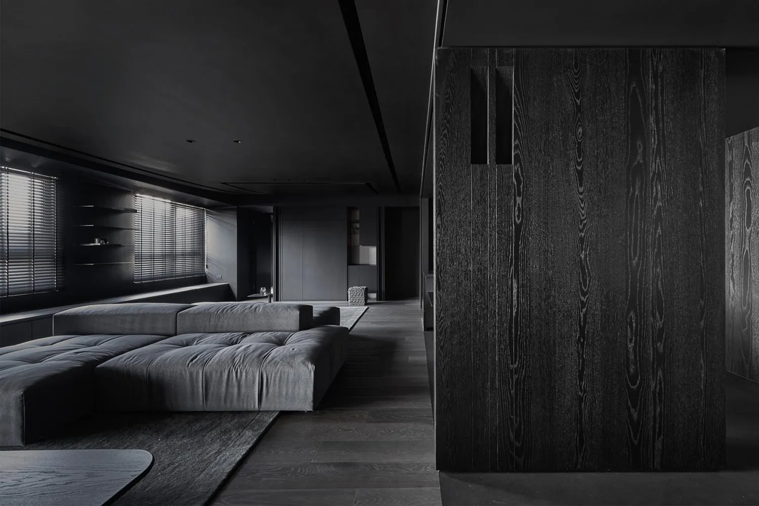 A modern minimalist living room with dark wood furniture and sleek, dark interior design.