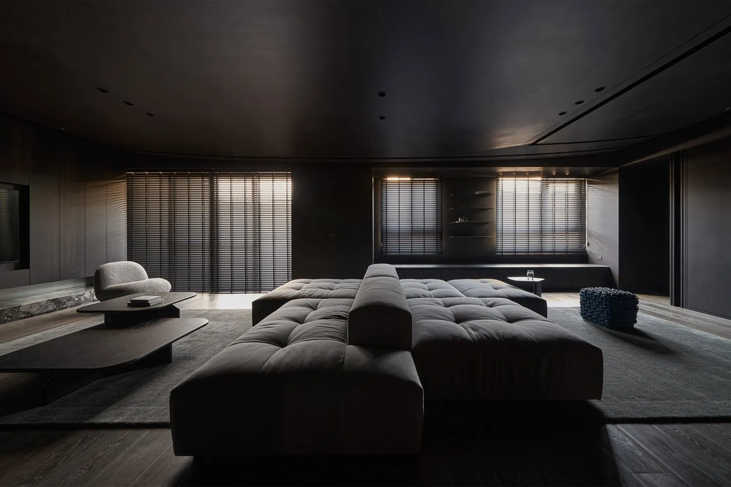 A modern living room with a large grey fabric couch, wooden coffee table, and dark wooden floor.