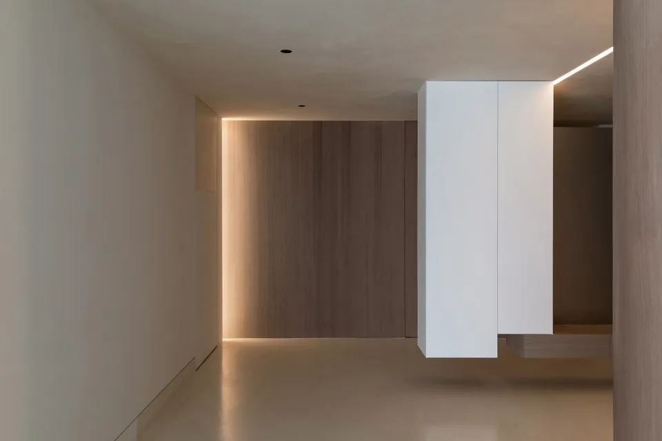 現代簡約辦公室室內,裸露混凝土牆面、俐落白色櫃體,以及溫暖燈光映照木質背景