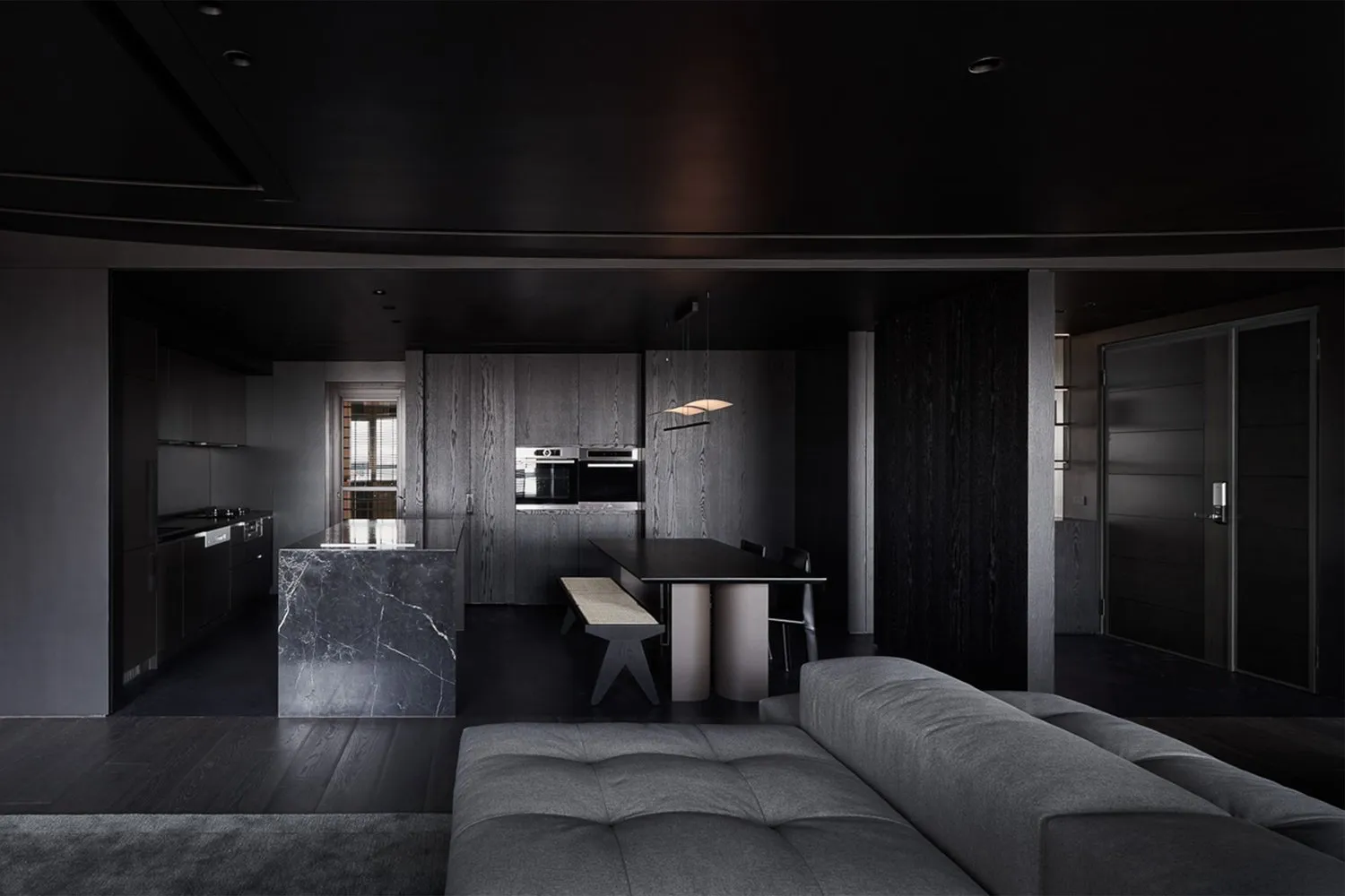 A modern kitchen with a sleek, minimalist design featuring a large marble island and dark wooden accents.