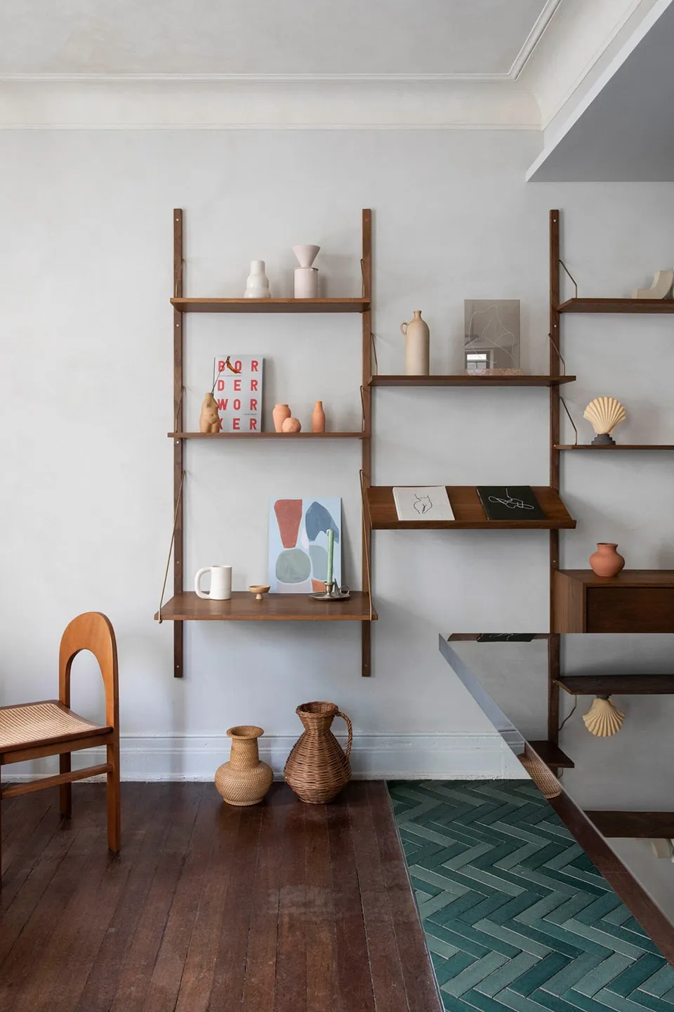 Minimalist floating shelves displaying various ceramic objects and books in a simple, modern interior design setting.
