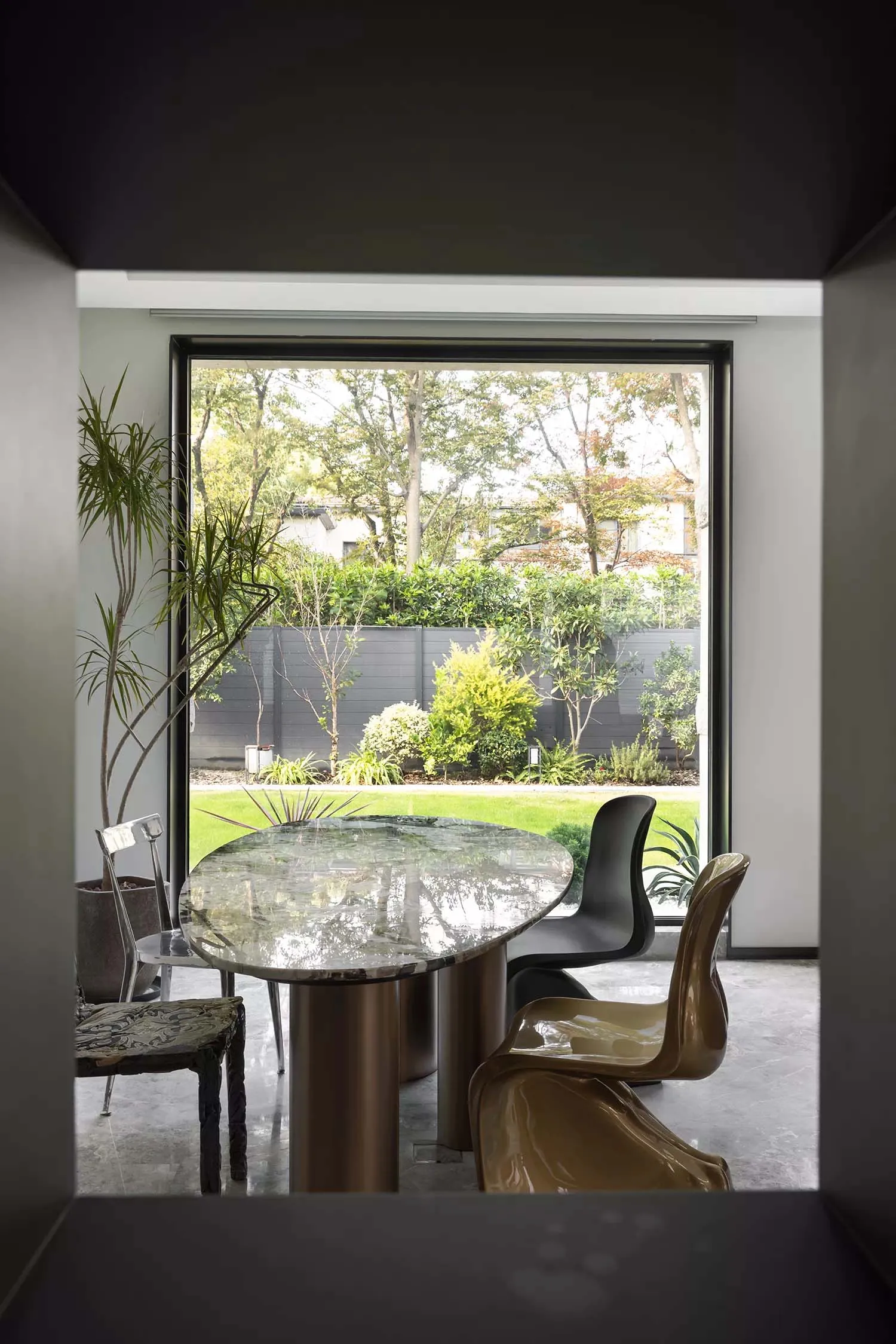Modern dining room featuring a round marble table with metal legs, surrounded by sleek chairs against a large window