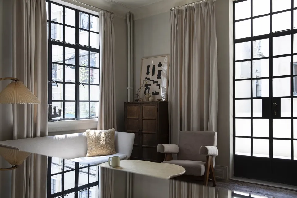 Modern living room featuring fabric furniture, wood accents, and glass windows with a minimalist decor.