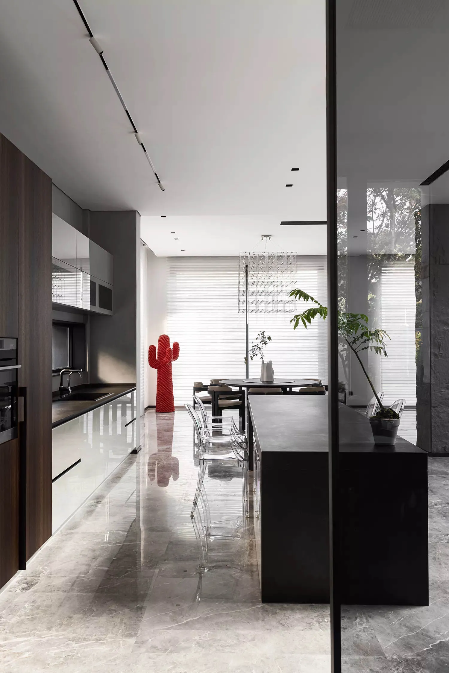 Modern kitchen with marble countertops and dining area with concrete floor and plants.