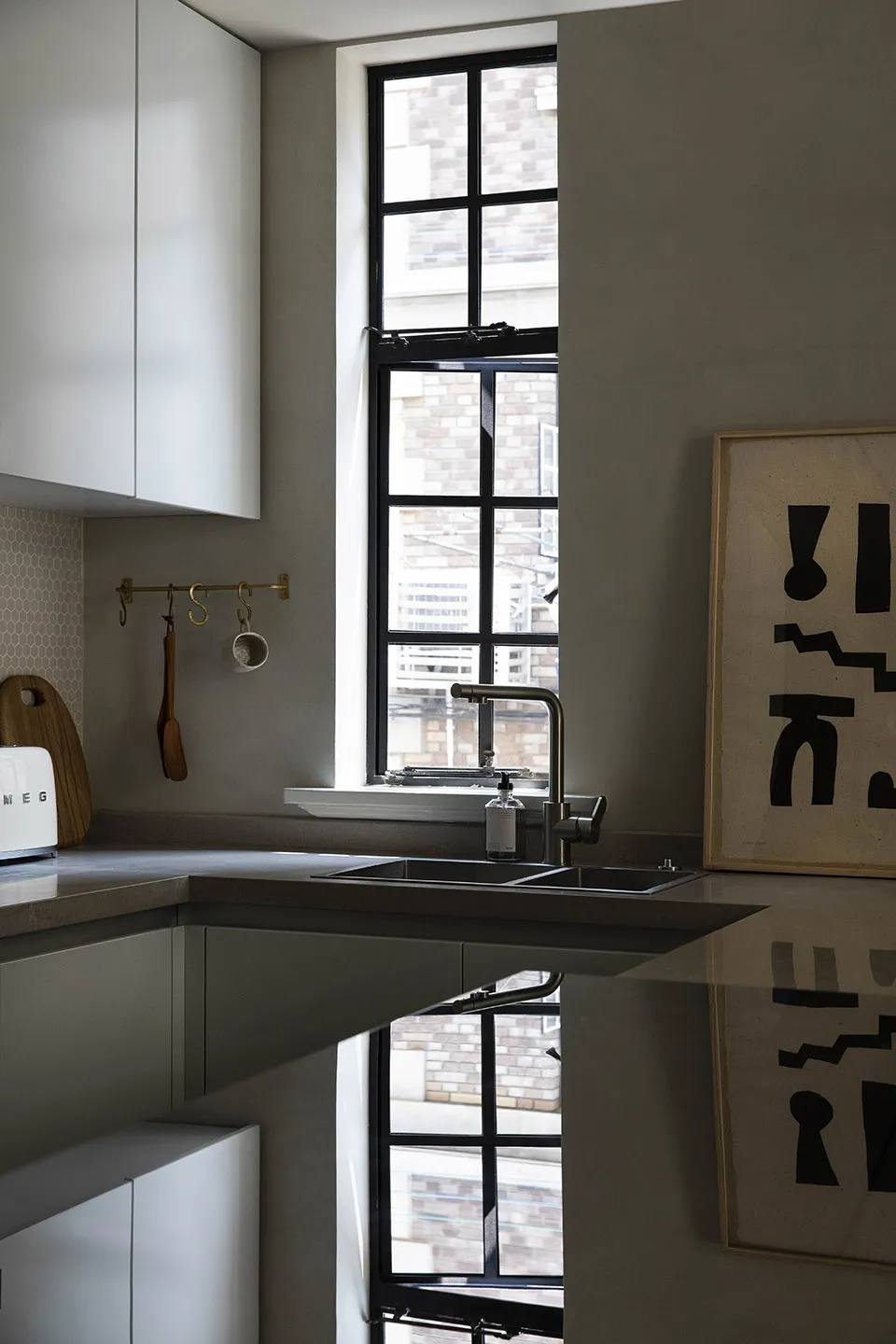Modern minimalist kitchen featuring a concrete countertop and flooring, with a sleek stainless steel sink and a large window