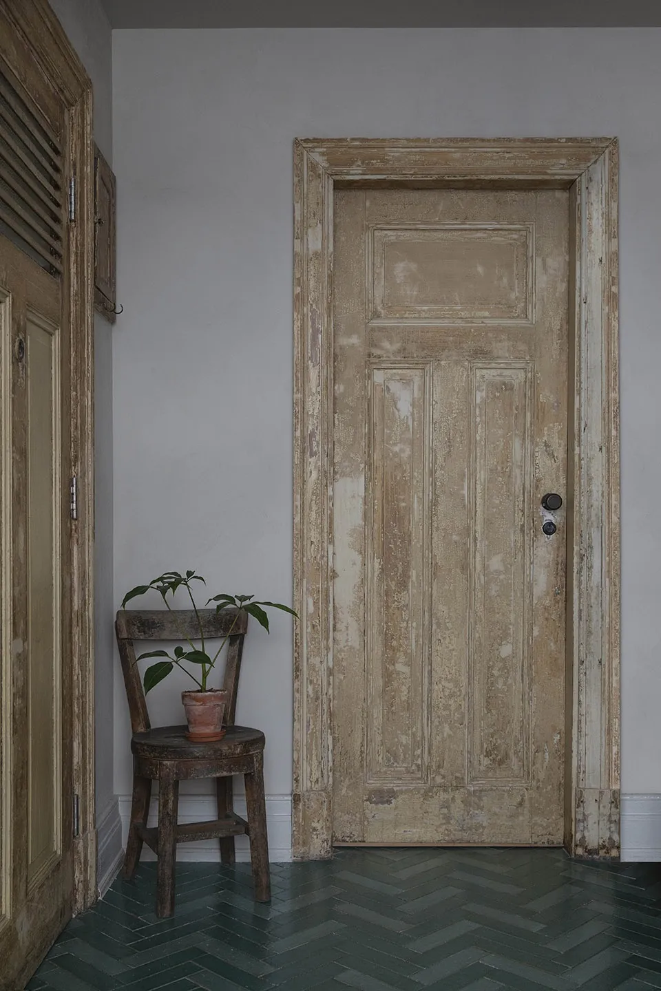 Vintage wooden door with peeling paint in an entryway setting.