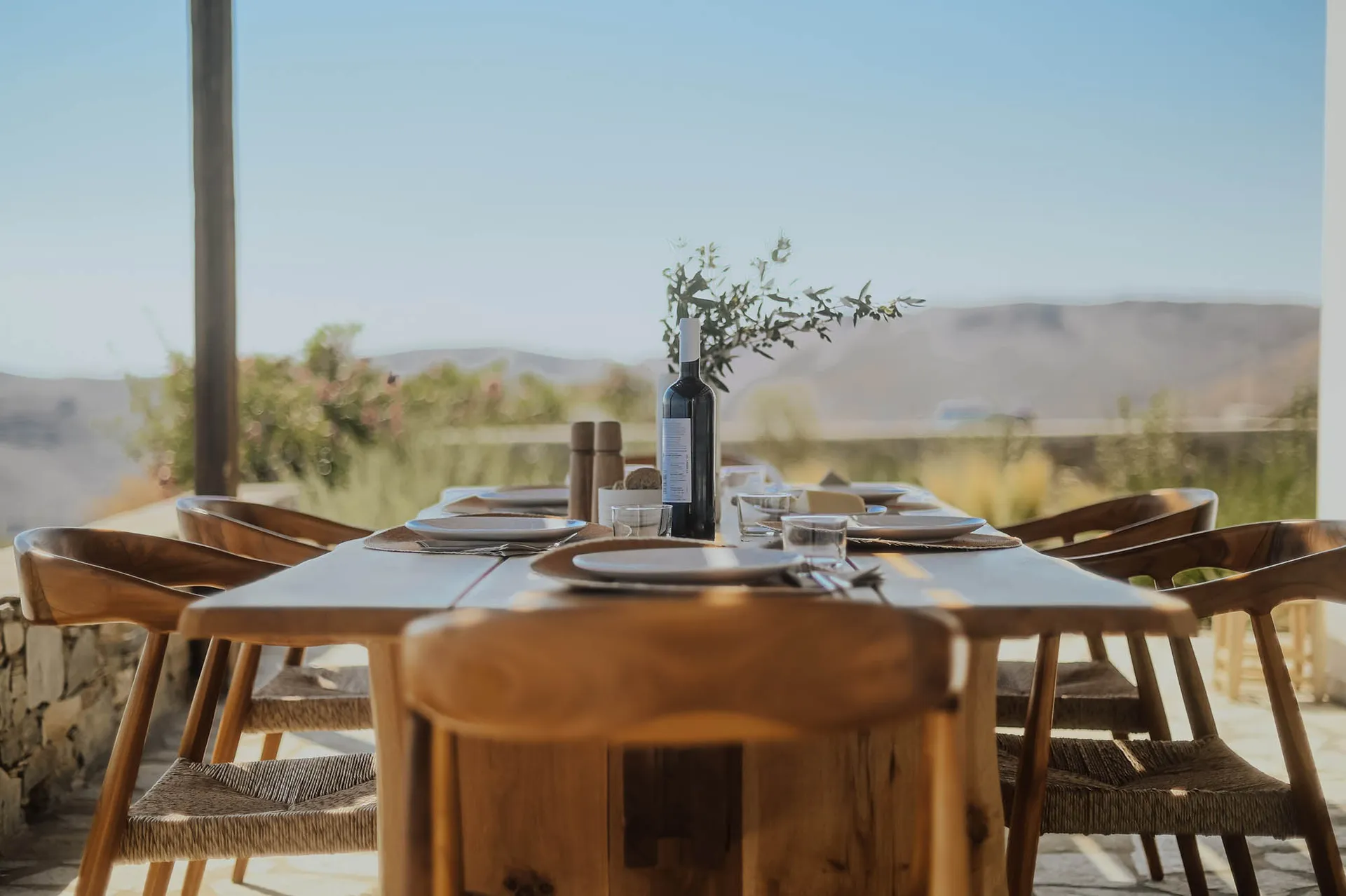 Outdoor dining area with a wooden table and chairs, set for a meal with a scenic mountain view.