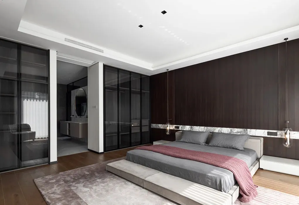 A modern minimalist bedroom with a wooden accent wall, glass sliding doors, and a platform bed.