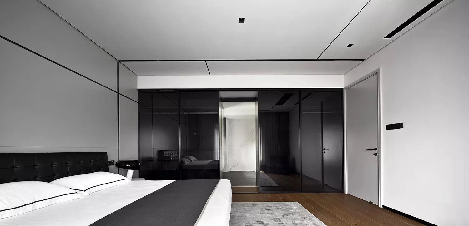 A modern bedroom with black and white decor, featuring glass cabinets and minimalist furniture.