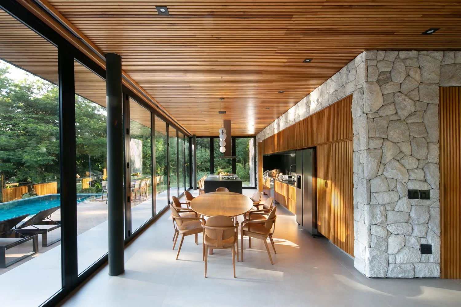 Modern residential kitchen with wood cabinets, stone accents, and glass windows.