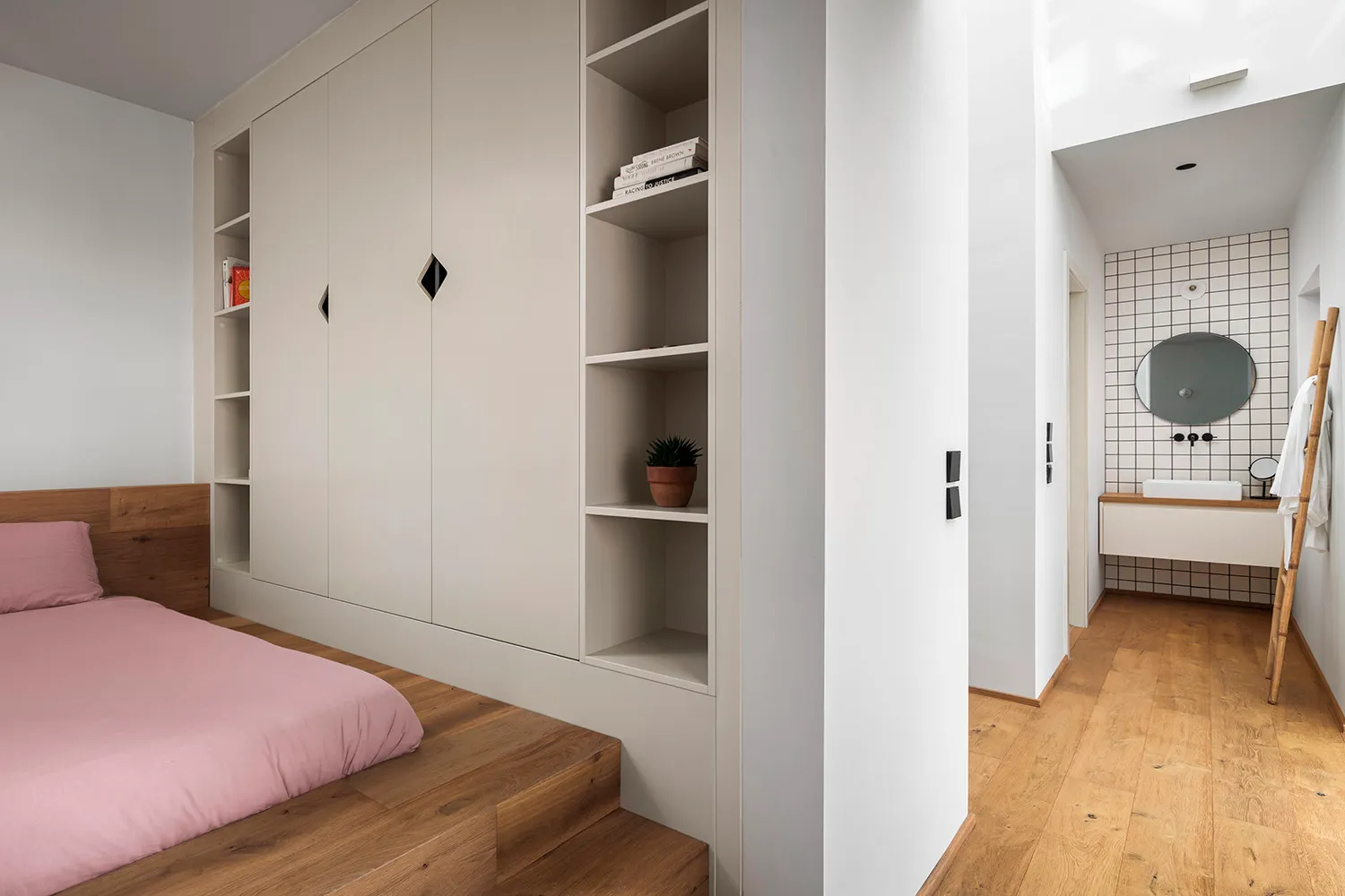 Minimalist bedroom with wooden floors, white walls, and built-in shelves.
