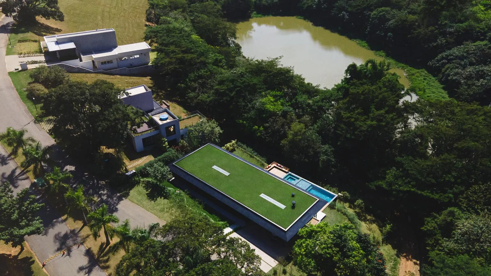 A modern residential exterior with greenery and a swimming pool.