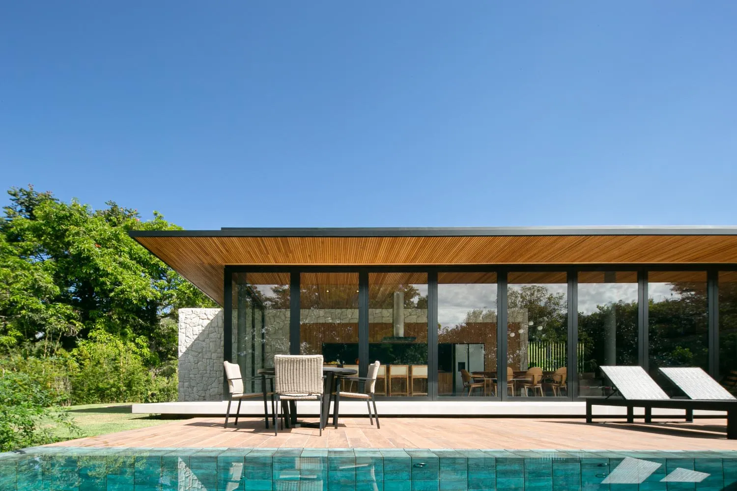 Modern residential exterior featuring glass, wood, and concrete materials.