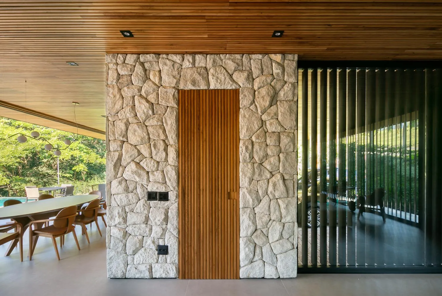 A modern doorway featuring a wooden door and stone wall.