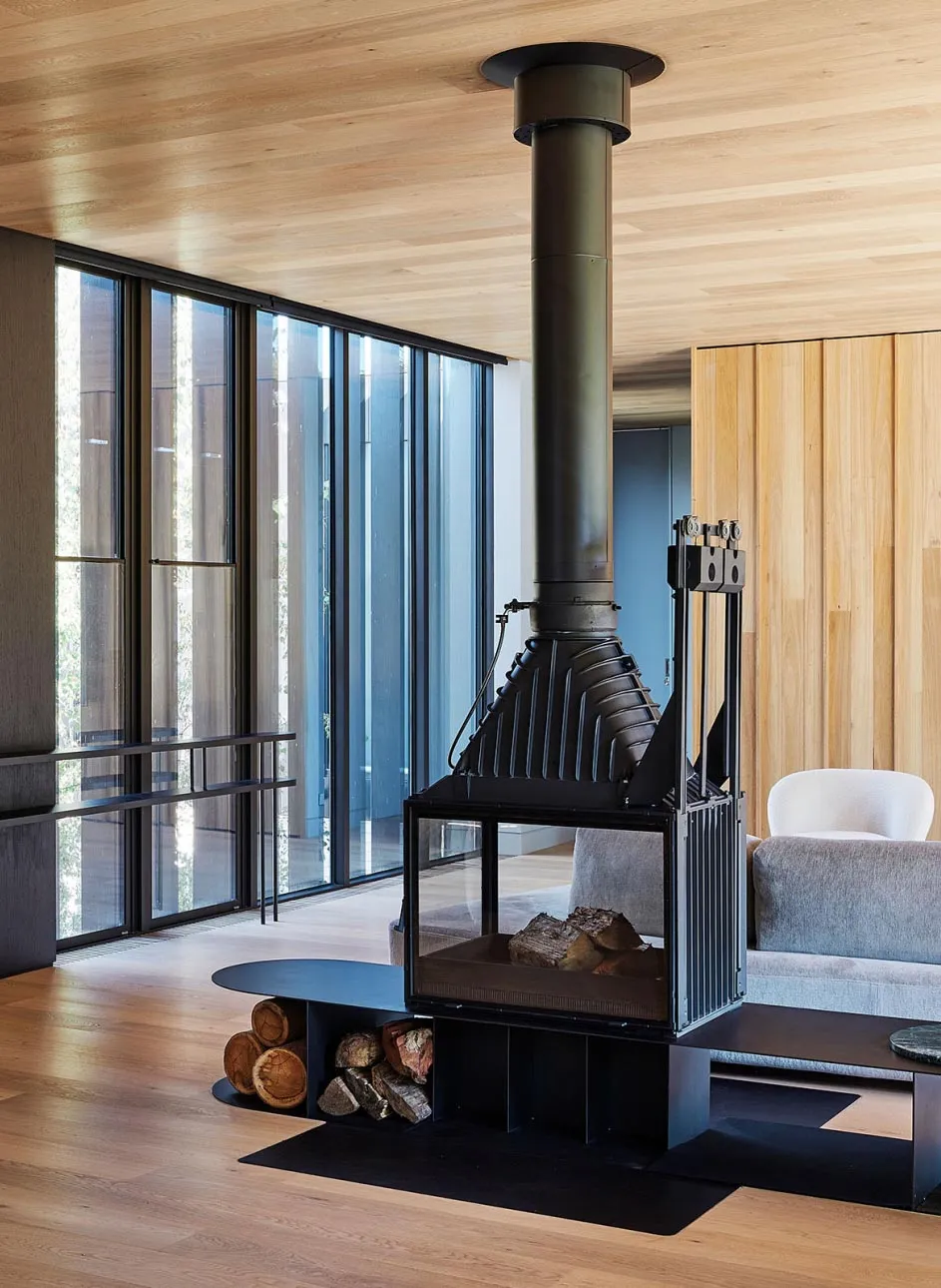 A modern living room featuring wooden walls and a fireplace with a tall chimney.